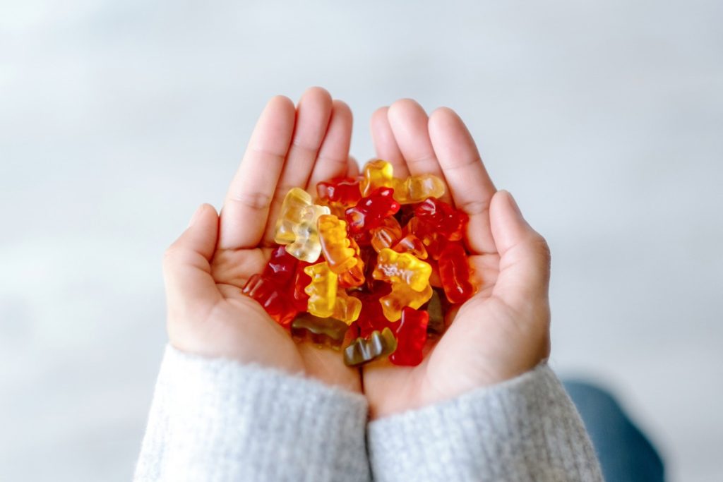A lady holding different flavors of nootropic mushrooms gummies