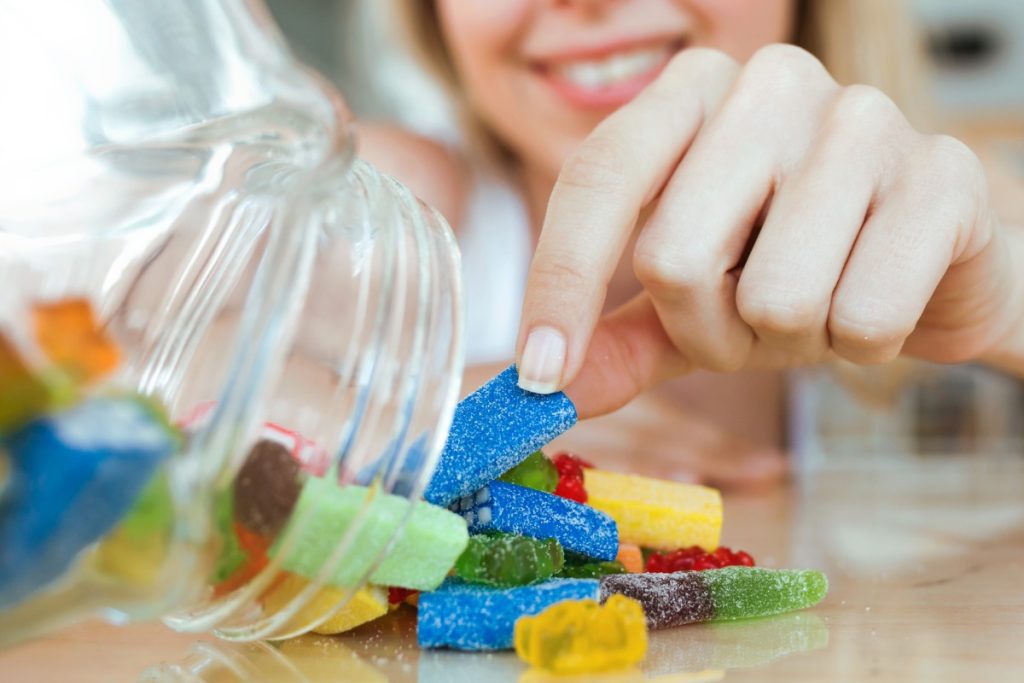 A lady is eating mushroom gummies from a jar